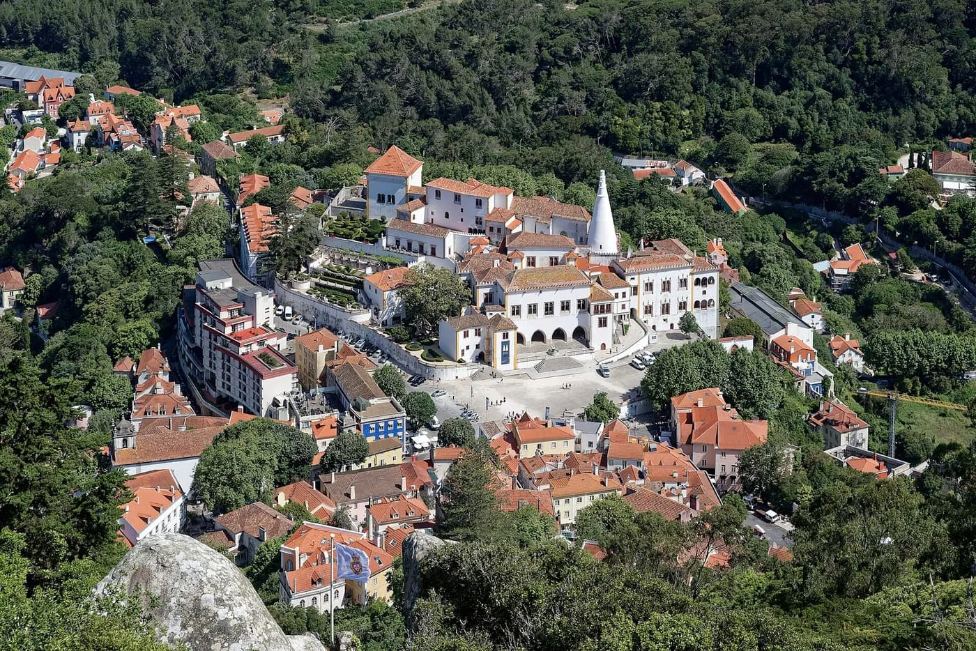 The white National Palace of Sintra with its conical chimneys among the trees, seen from the Moorish Castle