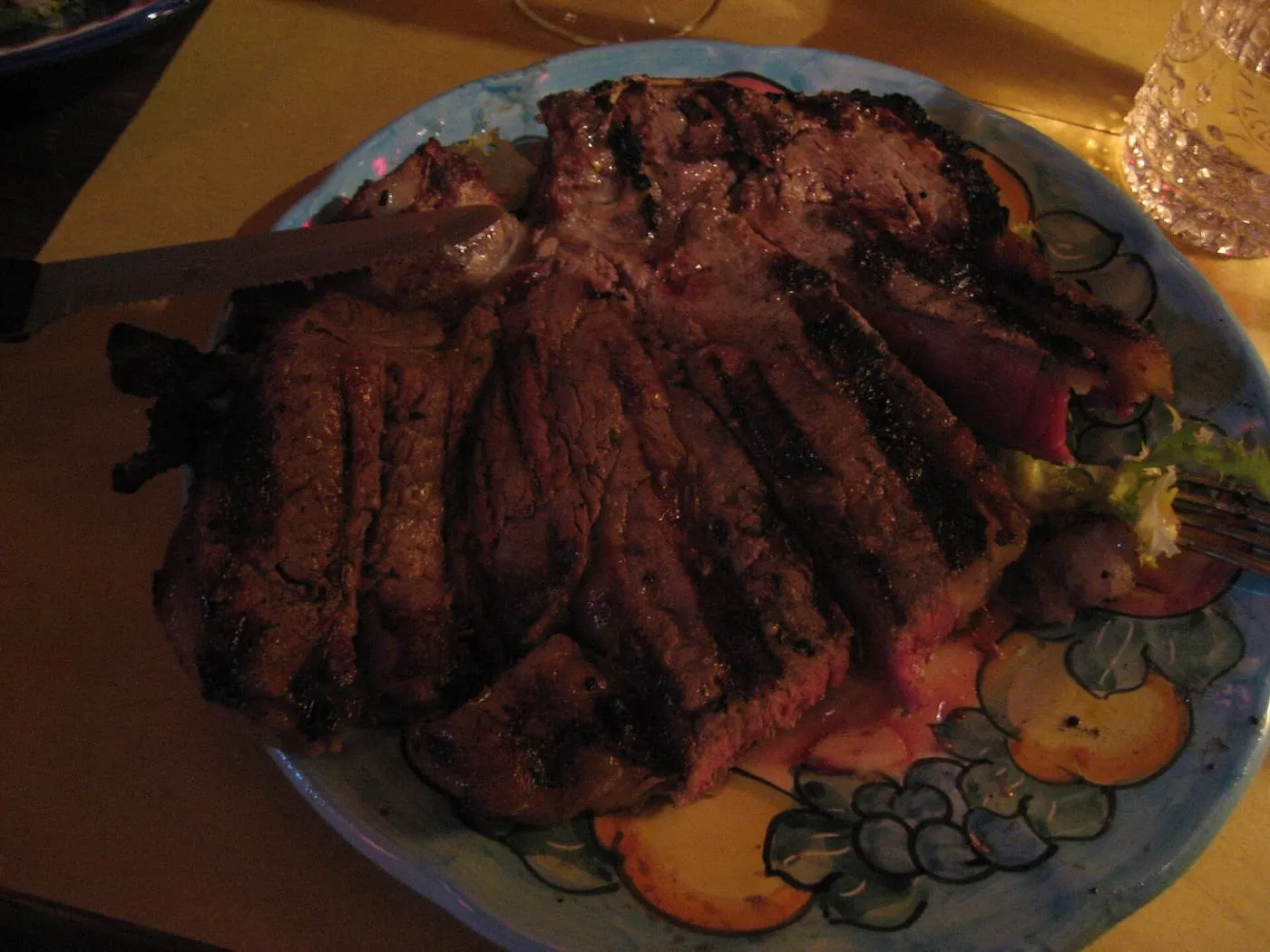 A bistecca alla fiorentina sliced from the bone on a painted ceramic plate, charred outside and rare in the middle