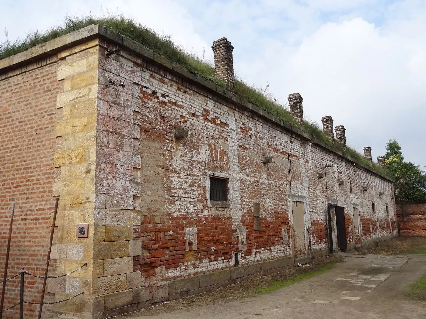 A long brick building with a grass-covered roof and a barred window in the Small Fortress at Terezín