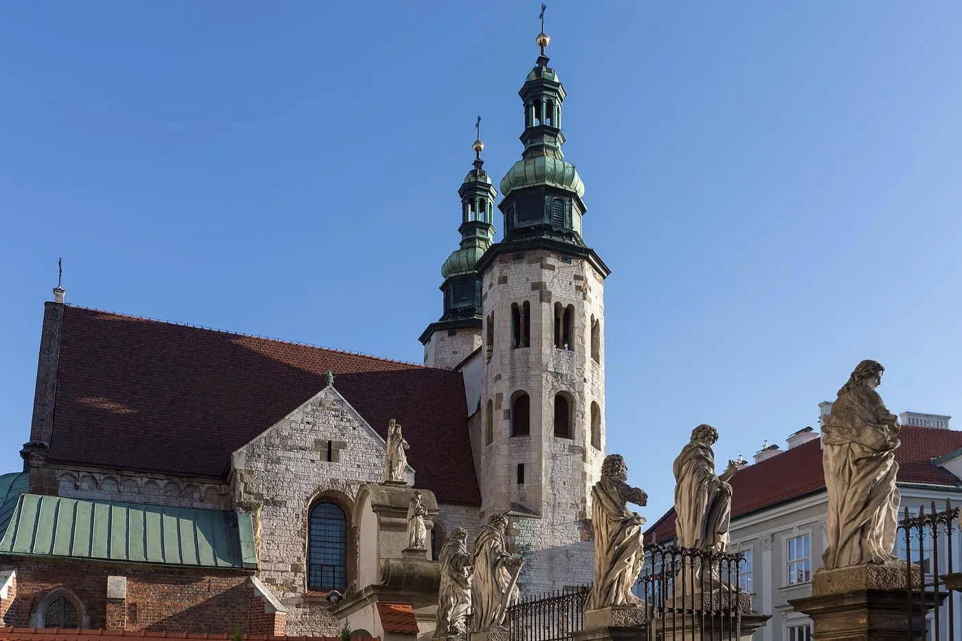 St Andrew's Church, a pale stone Romanesque church with two octagonal towers topped by green Baroque cupolas, behind statues of the apostles