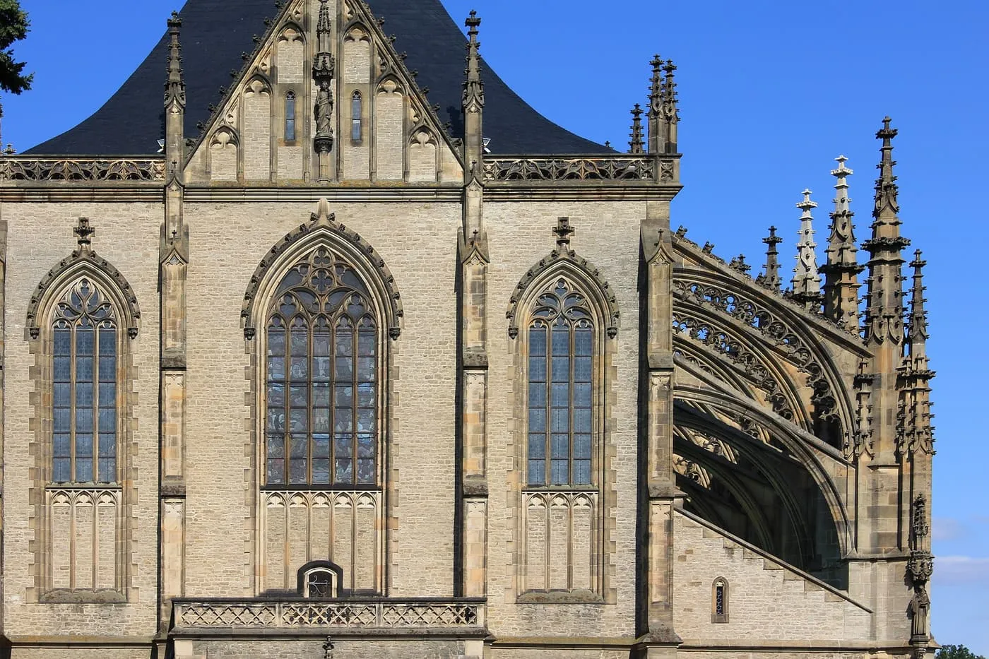 The east end of St Barbara's Cathedral in Kutná Hora, with tall pointed windows, flying buttresses and pinnacles under a blue sky