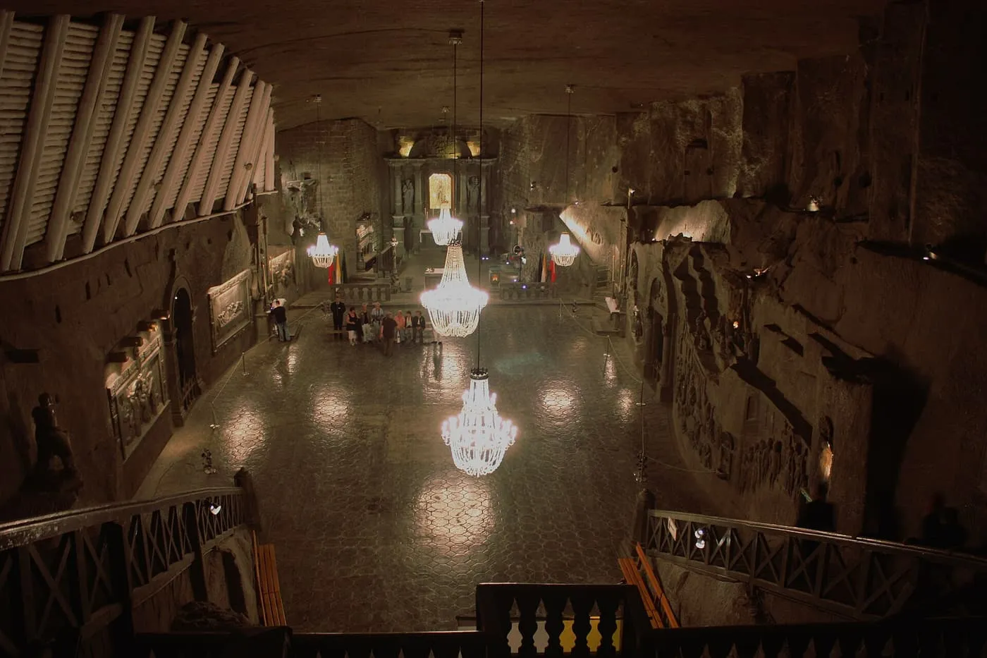 The Chapel of St Kinga seen from the stairs, with chandeliers hanging over a paved floor and carved reliefs on the rock walls