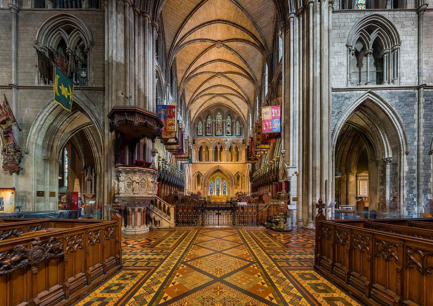 The nave of St Patrick's Cathedral looking towards the choir, with carved stalls, a tiled floor and a vaulted ceiling