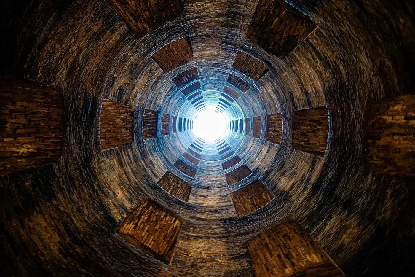 Looking up the shaft of St Patrick's Well in Orvieto, with light at the top and brick steps spiralling round the walls