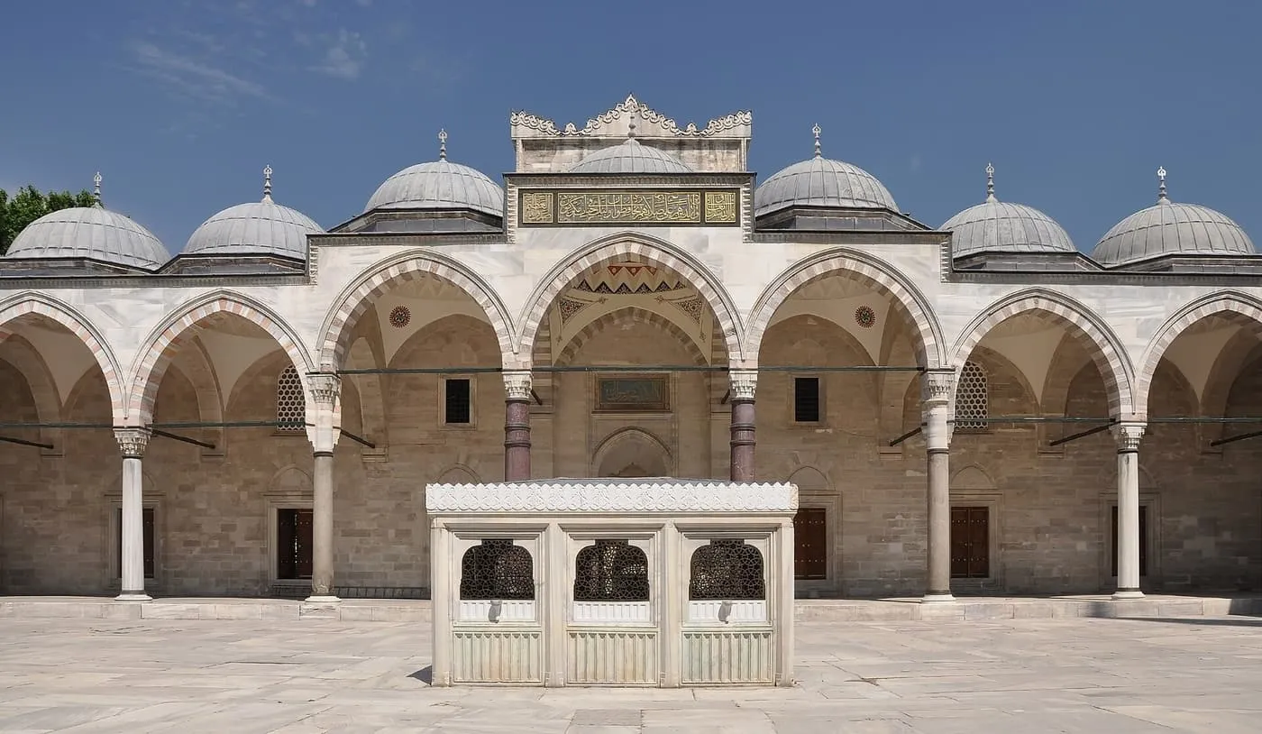 The arcaded courtyard of the Süleymaniye Mosque with a small marble ablution fountain on the paving in front