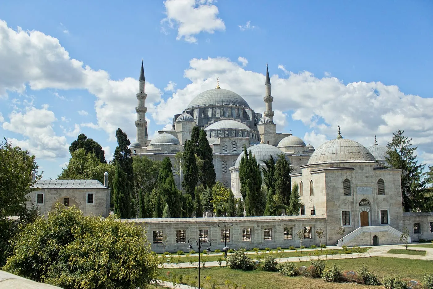 The Süleymaniye Mosque across a lawn and low precinct wall: a cascade of domes and two minarets under a blue sky