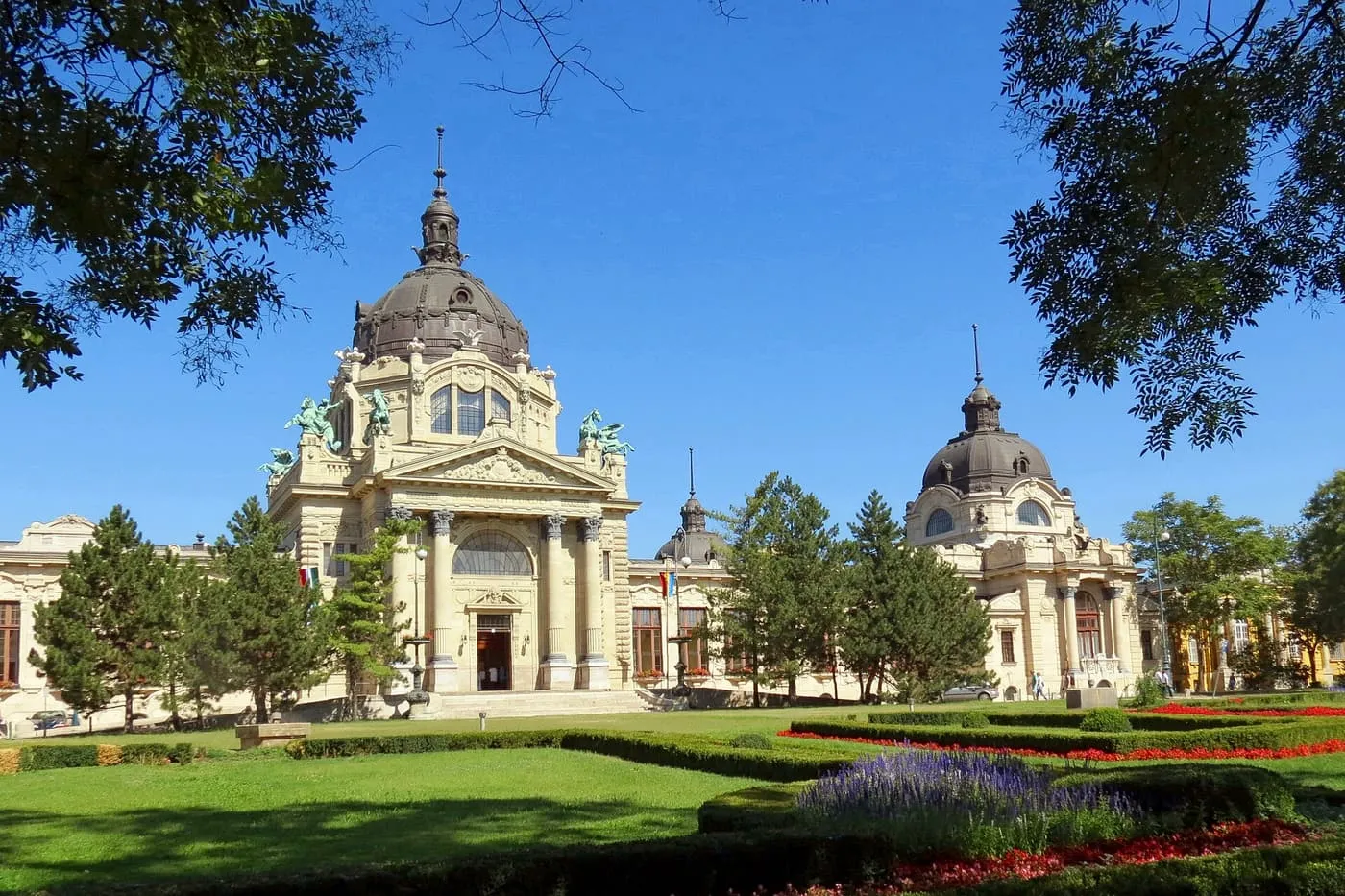 The domed main building of the Széchenyi Baths seen across a flower bed in the City Park