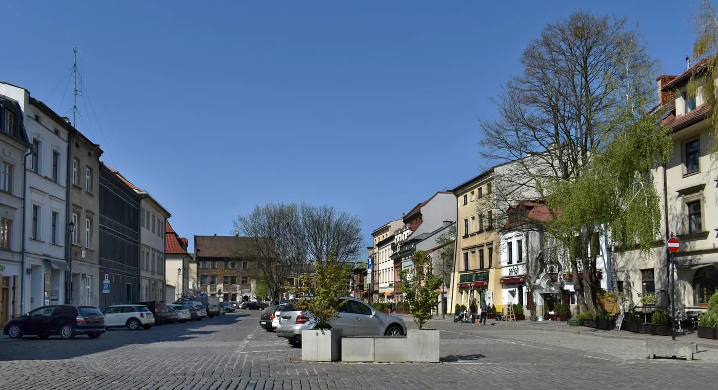 Szeroka Street in Kazimierz, a wide cobbled square lined with tenement houses and trees