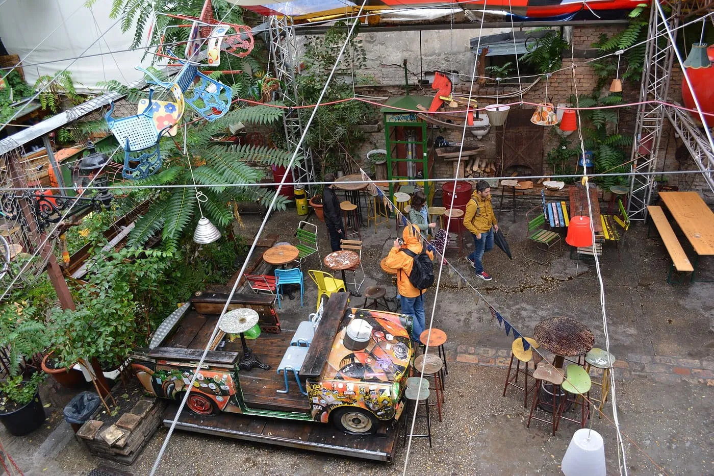 Looking down into Szimpla Kert's courtyard, with a painted car body among mismatched chairs, tables and hanging lamps