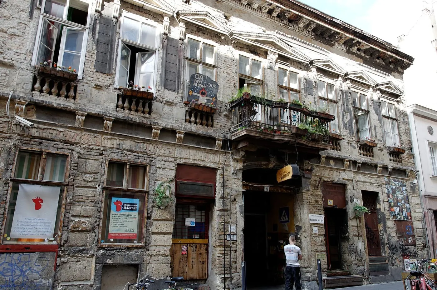The crumbling stone front of the Szimpla Kert building on Kazinczy utca, with an open archway into the courtyard