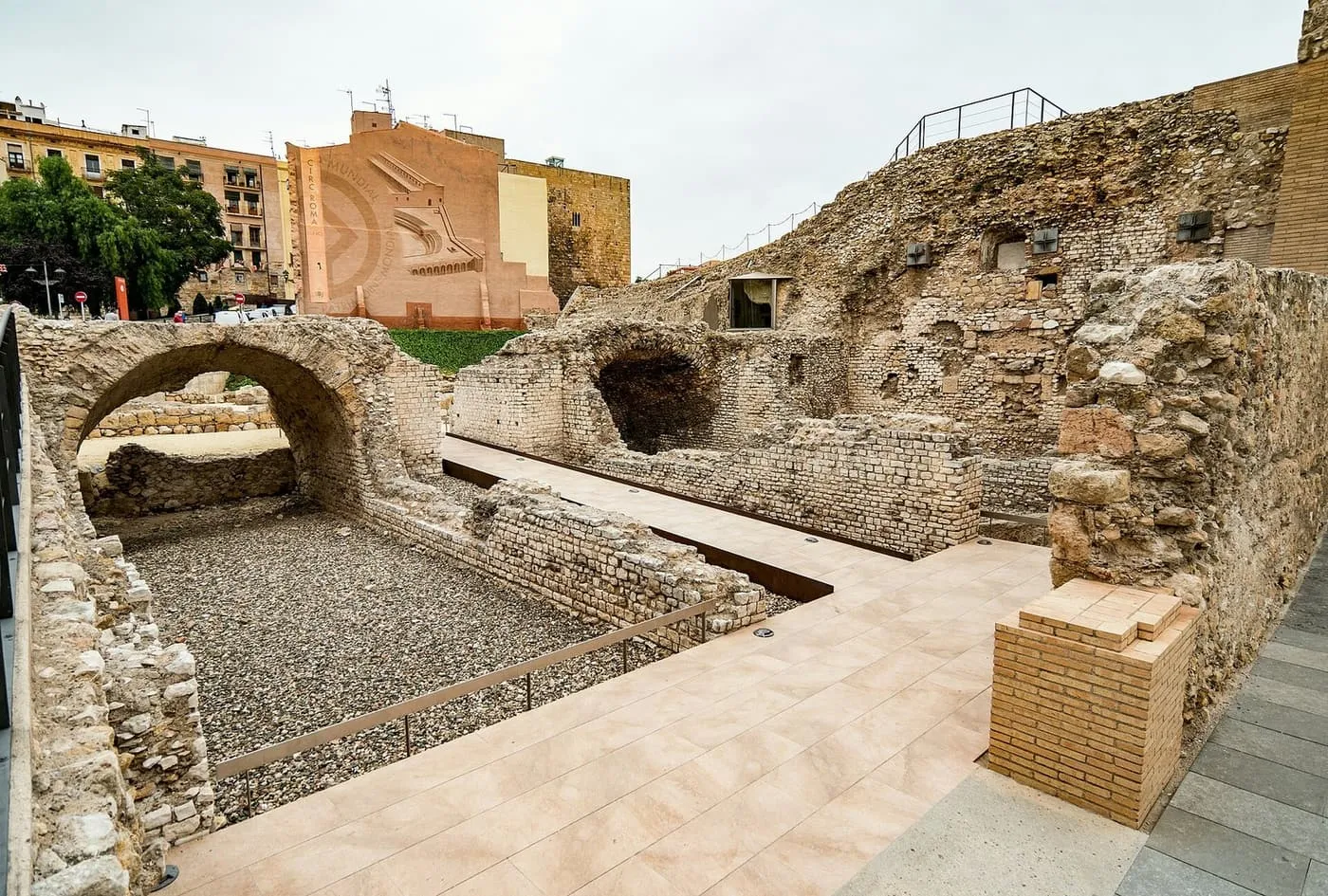Excavated vaulted stone passages of Tarragona's Roman circus, with the old town's buildings above