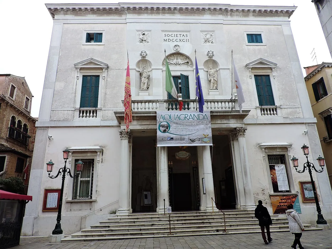 The pale neoclassical front of La Fenice on Campo San Fantin, with a banner above the entrance