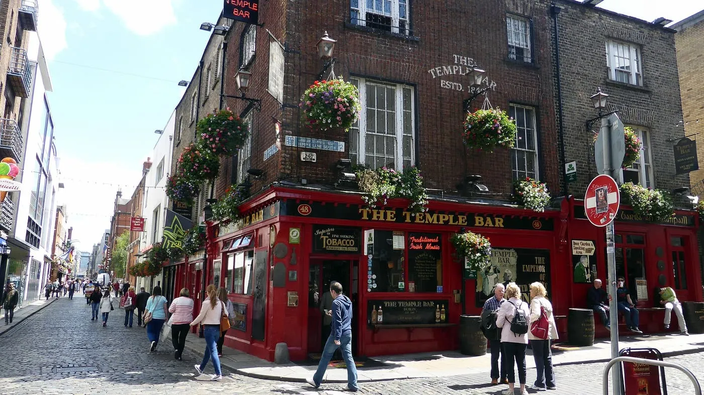 The red front of the Temple Bar pub with hanging baskets on the corner of a cobbled street