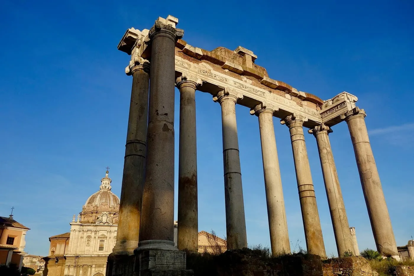 The standing columns of the Temple of Saturn in the Roman Forum against a clear blue sky