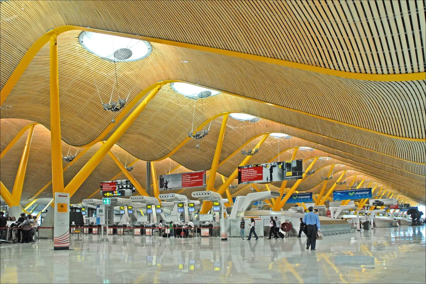 The undulating bamboo roof of Madrid-Barajas Terminal 4, held up by yellow steel supports, above a row of check-in desks