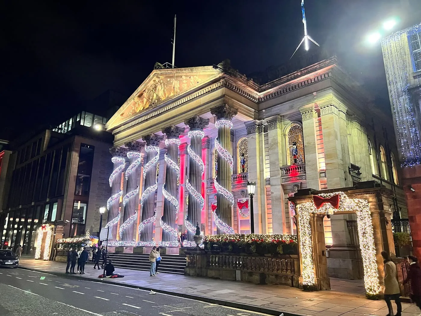 The columns of The Dome on George Street wound with white lights, a lit archway at the gate and bows on the railings, at night