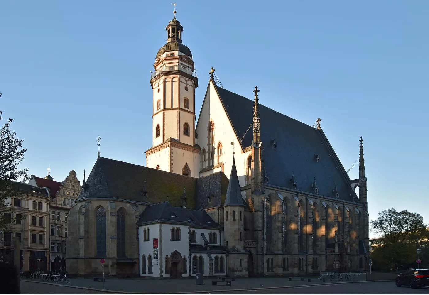 The Thomaskirche in Leipzig, with its steep slate roof and white bell tower, in low sunlight