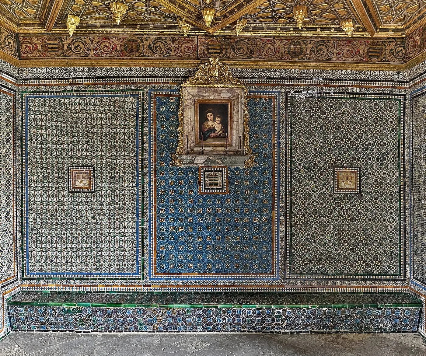 Blue and green glazed tiles covering the walls of the staircase landing, with a framed painting of the Virgin and Child and a gilded ceiling above