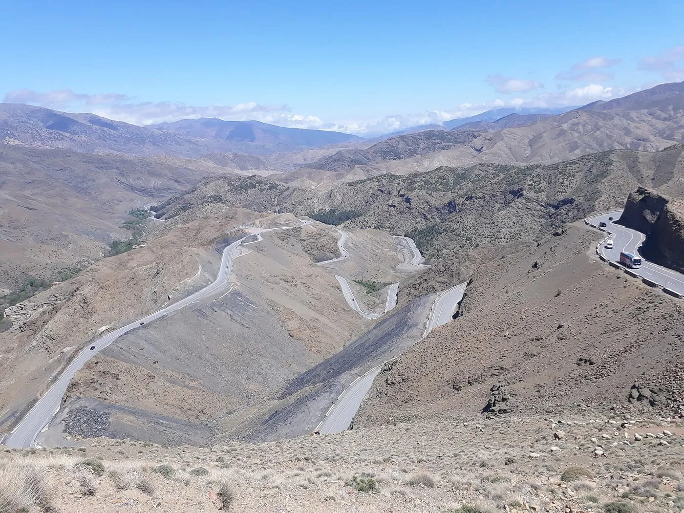 Hairpin bends of the road over the Tizi n'Tichka pass winding down a bare mountainside, with a coach on a bend