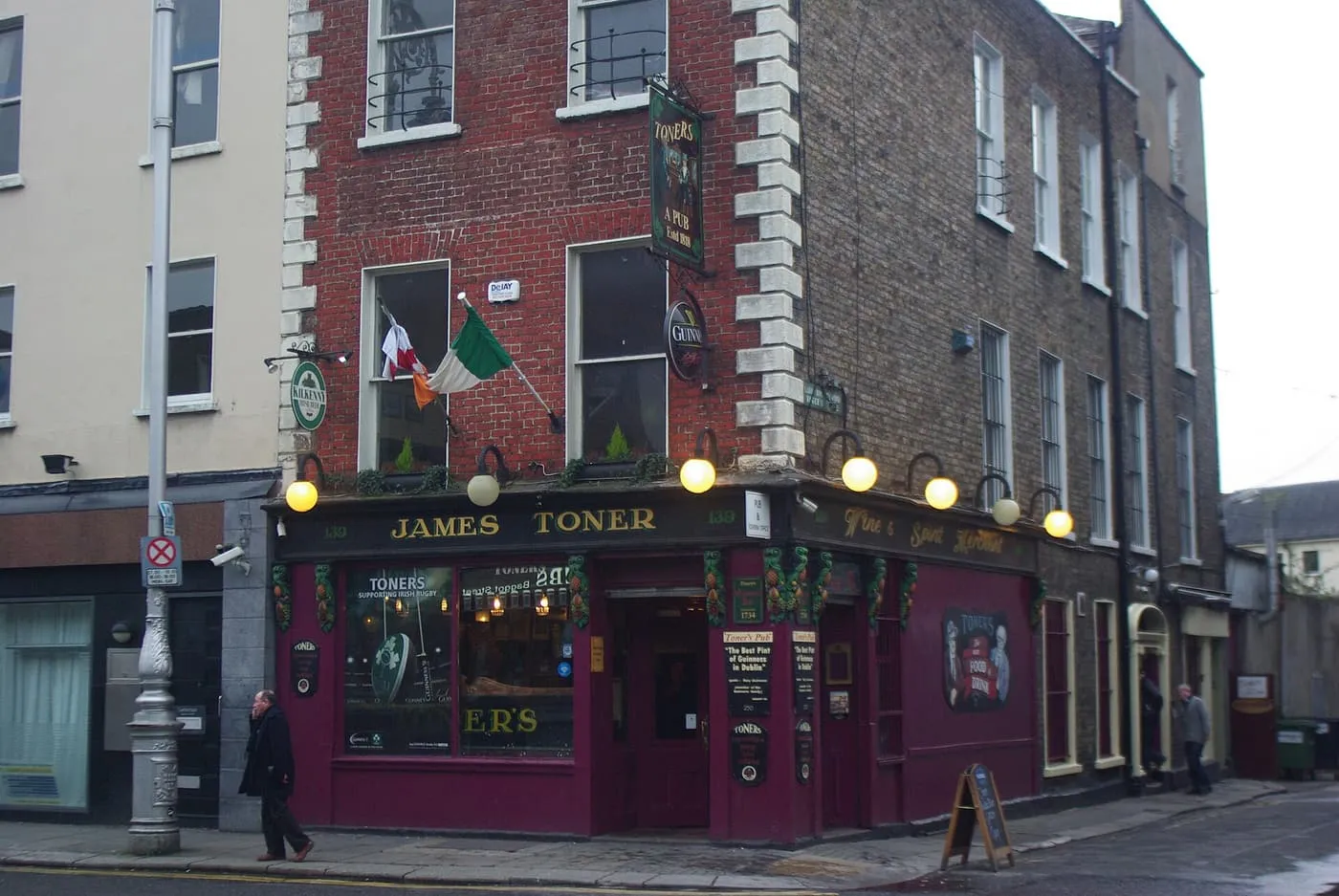 The maroon-painted front of Toners pub on the corner of Lower Baggot Street, with an Irish flag above the door
