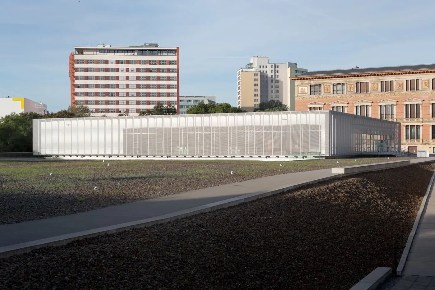The Topography of Terror documentation centre, a low pale building with a translucent facade, behind a field of gravel