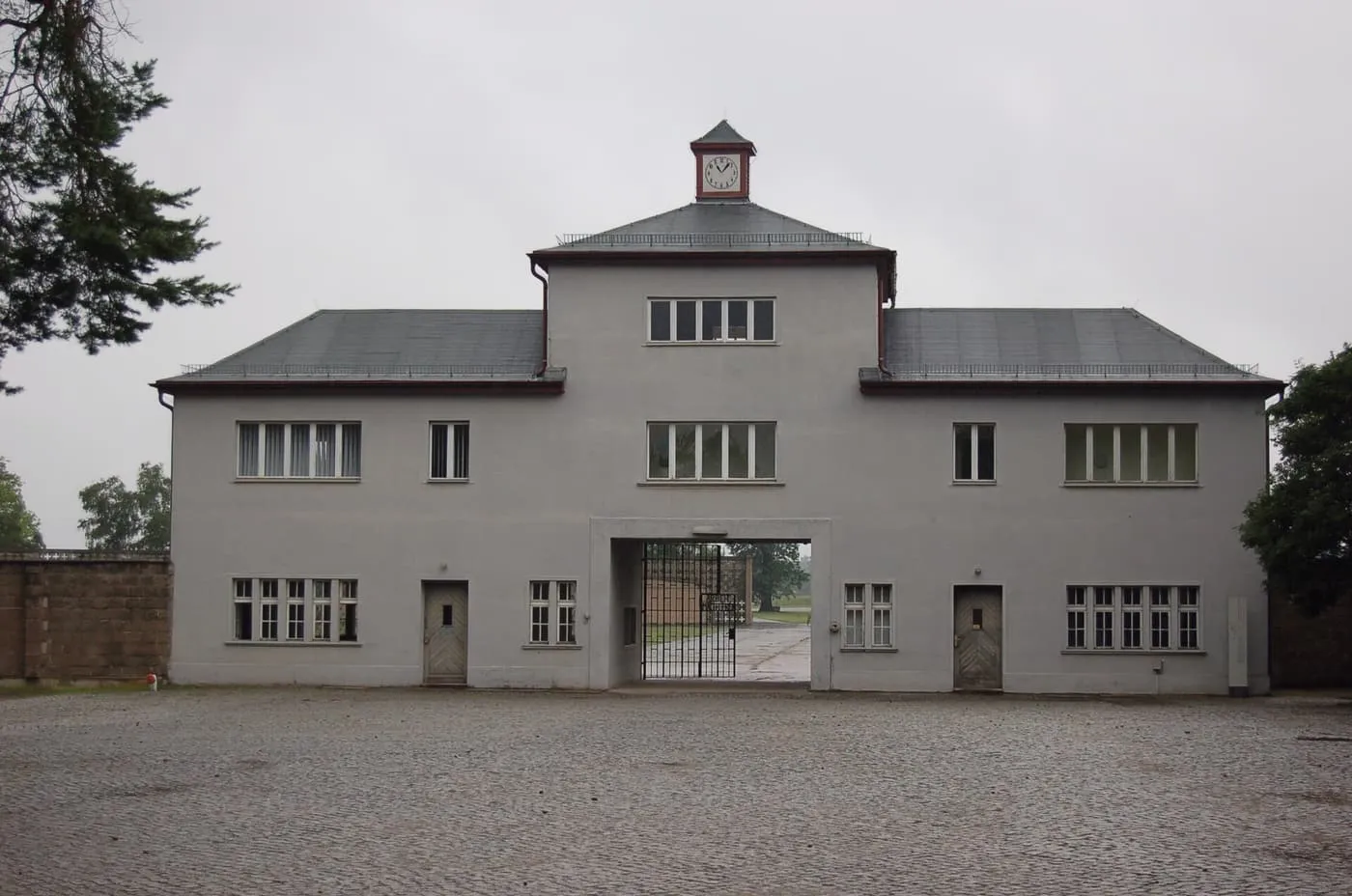 Tower A, the grey gatehouse at the entrance to the former Sachsenhausen camp, seen across an empty cobbled square