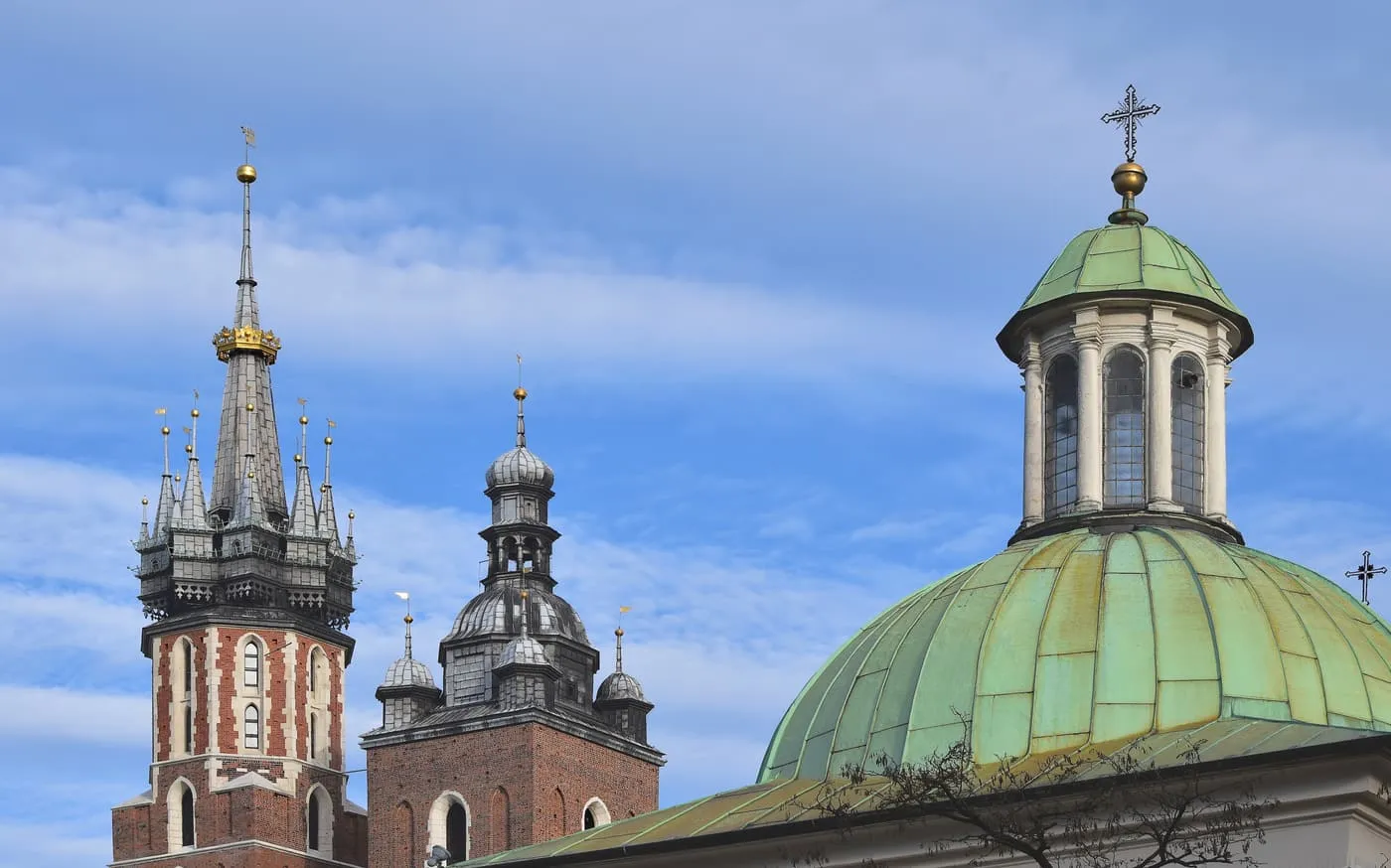 The two towers of St Mary's Basilica, the taller with a golden crown on its spire, beside the green dome of St Adalbert's Church
