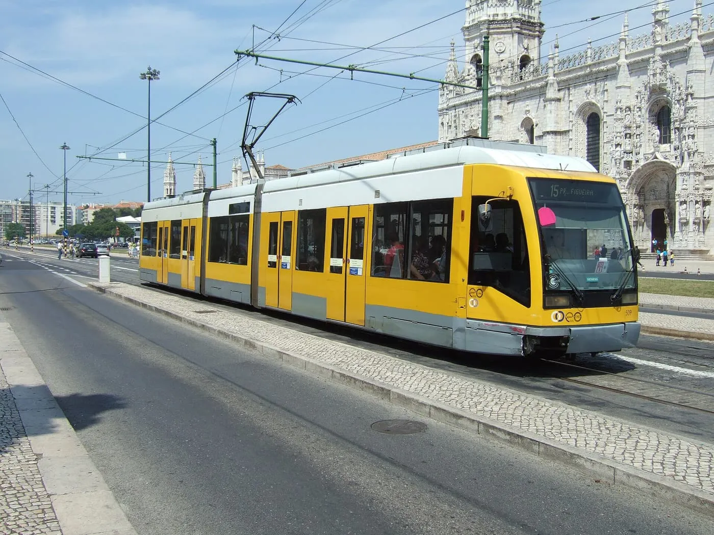 A yellow and grey articulated tram on line 15 passing the Jerónimos Monastery in Belém