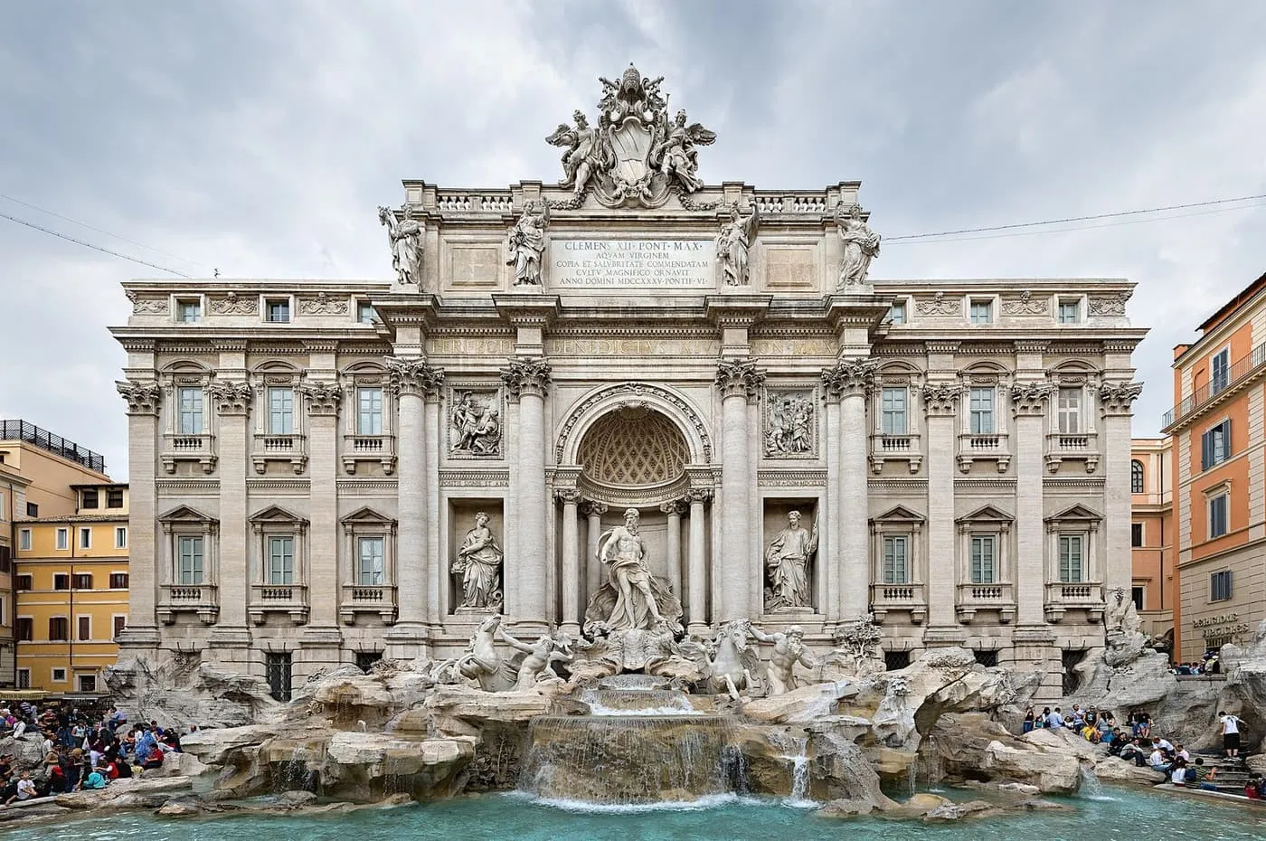 The Trevi Fountain's palace front and its Oceanus figure, with visitors sitting around the basin