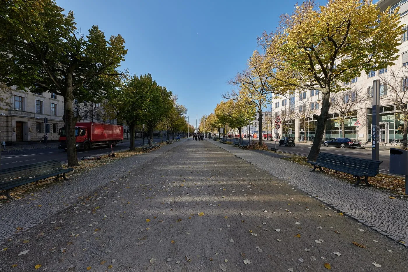 The tree-lined central promenade of Unter den Linden with benches and yellowing lime leaves