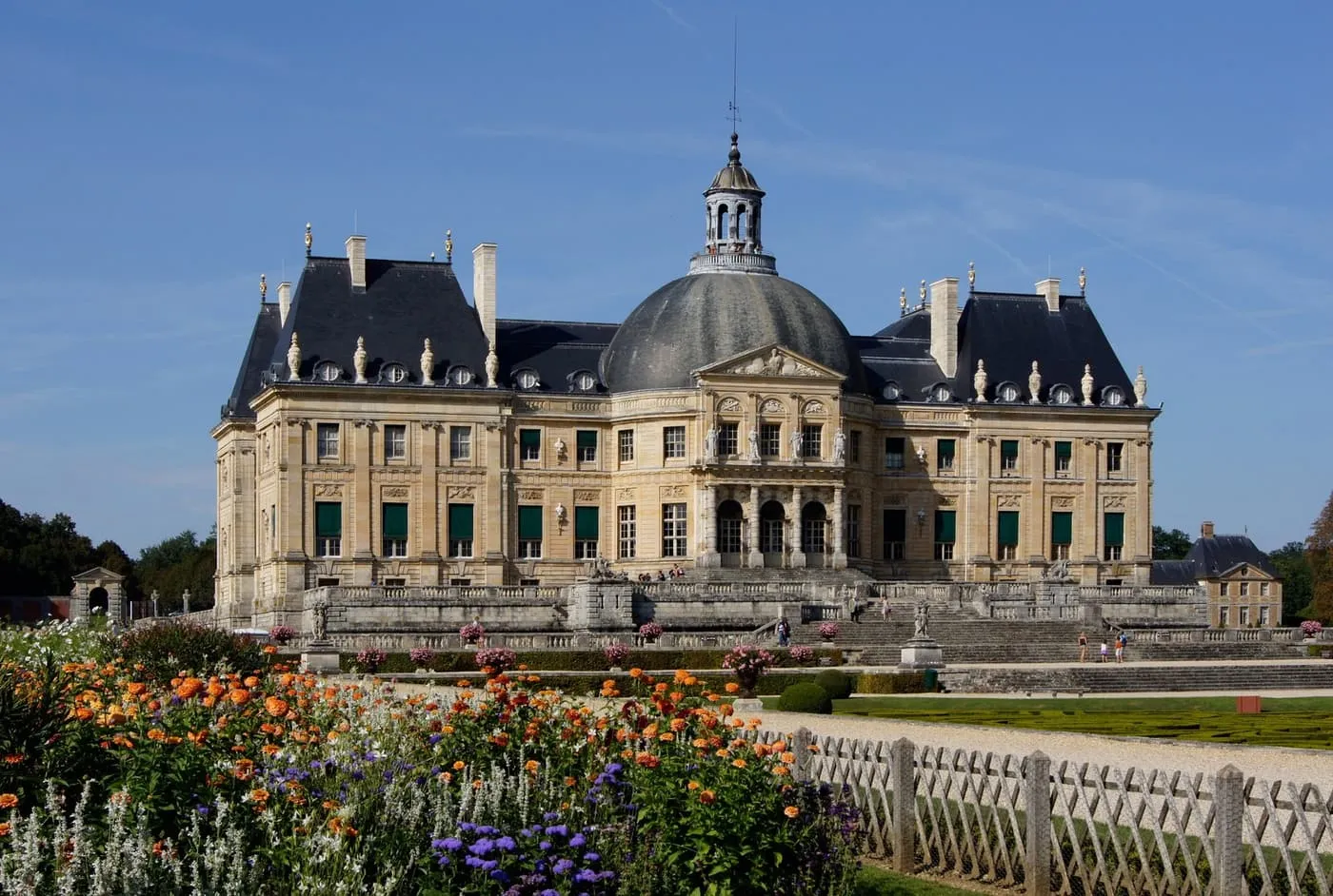 The garden front of the Château de Vaux-le-Vicomte with its domed central pavilion, seen over a bed of orange and purple flowers
