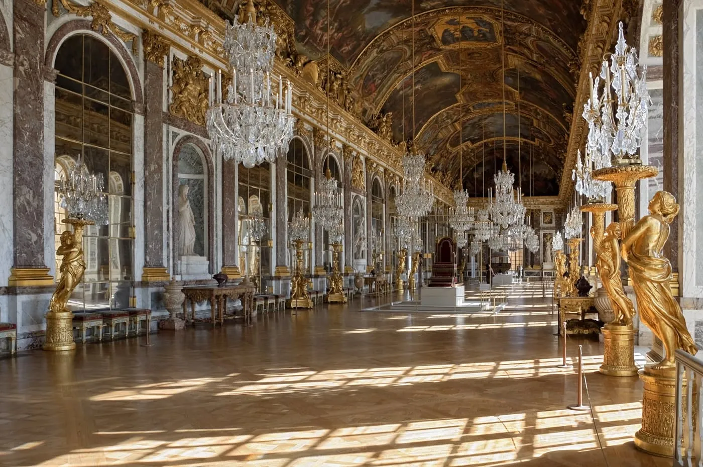 Crystal chandeliers, gilded statues and arched mirrors along the Hall of Mirrors at Versailles