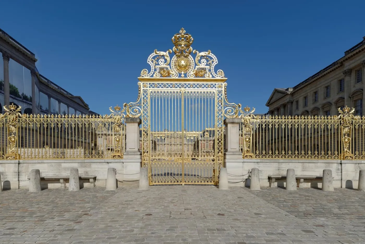 The gilded Grille Royale in front of the Palace of Versailles under a clear blue sky