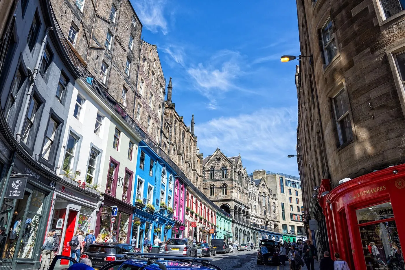 Victoria Street curving downhill between painted shopfronts in blue, white, pink and green and tall stone tenements