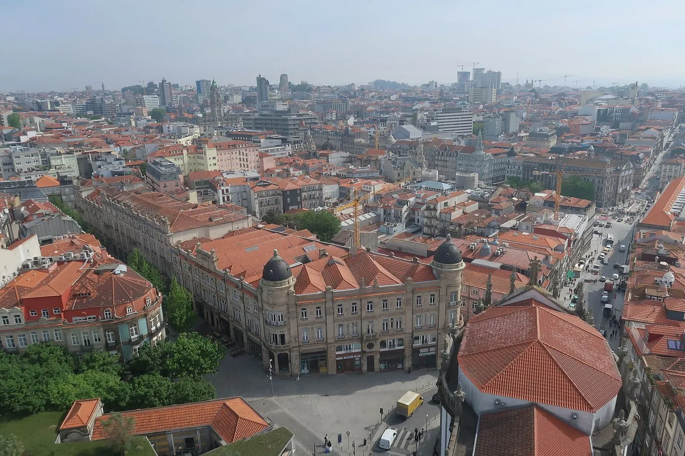 Terracotta rooftops, a green square and a domed corner building in central Porto, seen from the top of the tower