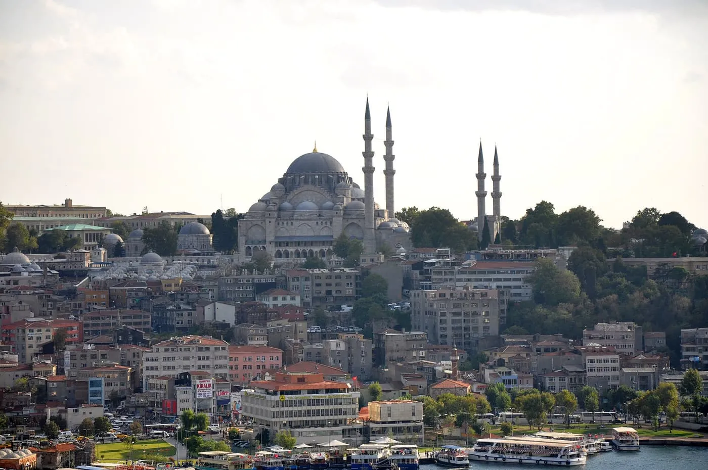The Süleymaniye Mosque with its four minarets on a hill above the rooftops, ferries at the waterfront below