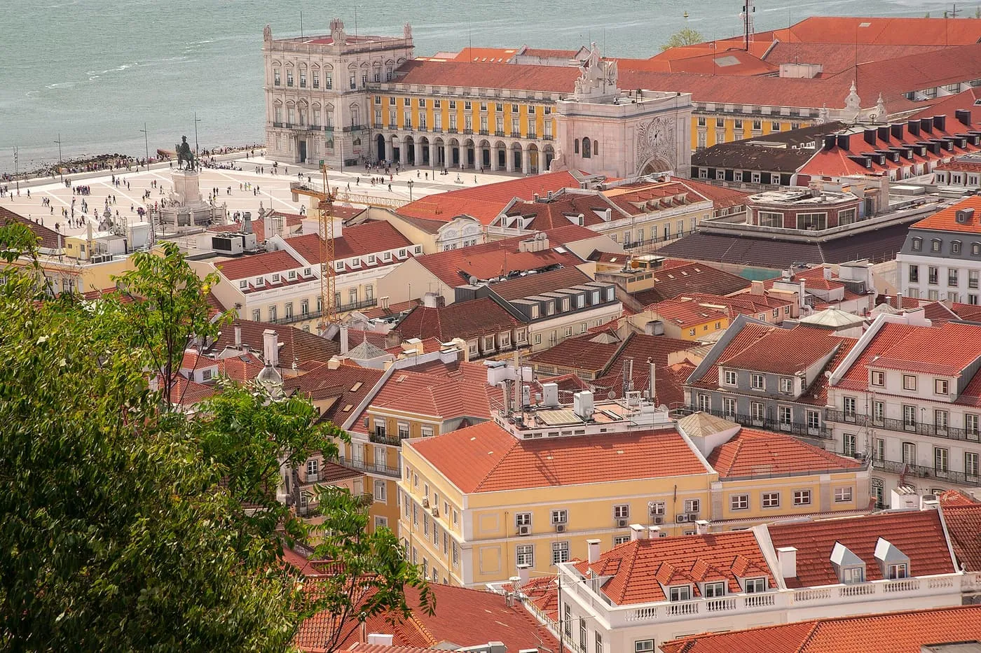 Terracotta roofs in Baixa, with the Praça do Comércio and the Tagus beyond