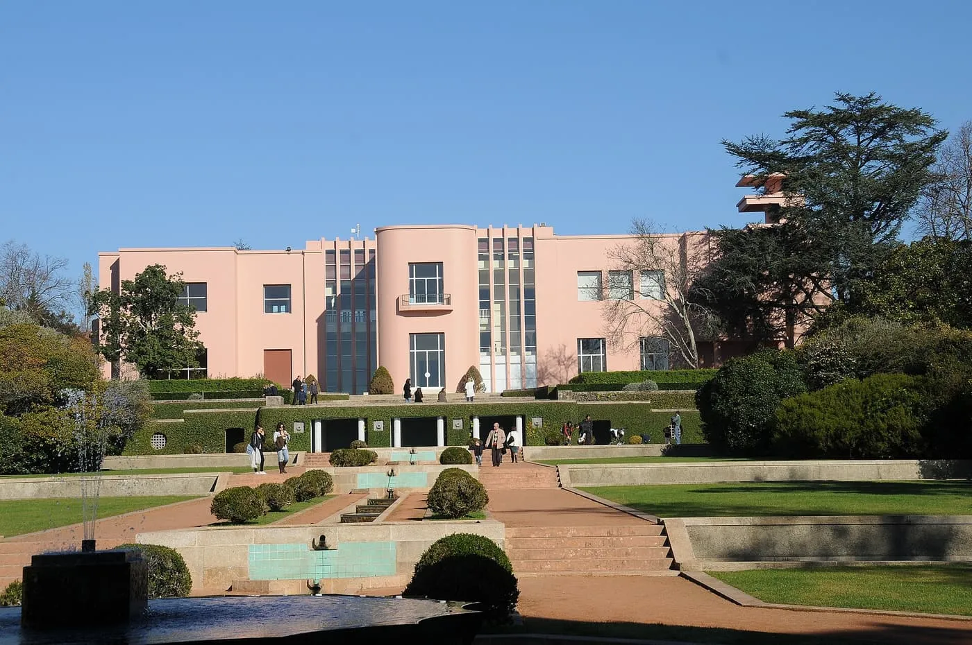 The pink Art Deco Serralves Villa seen across its terraced formal garden, with a fountain in the foreground
