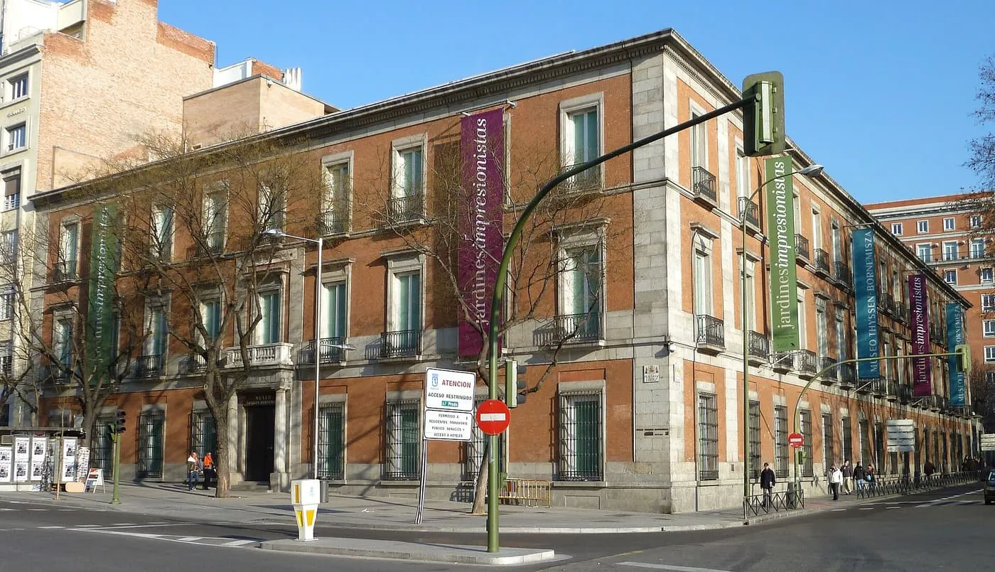 The red-brick and granite façade of the Villahermosa Palace, home of the Thyssen-Bornemisza Museum, on the corner of the Paseo del Prado