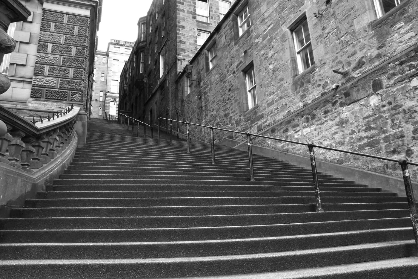 A long flight of stone steps climbing between tall tenement walls, in black and white